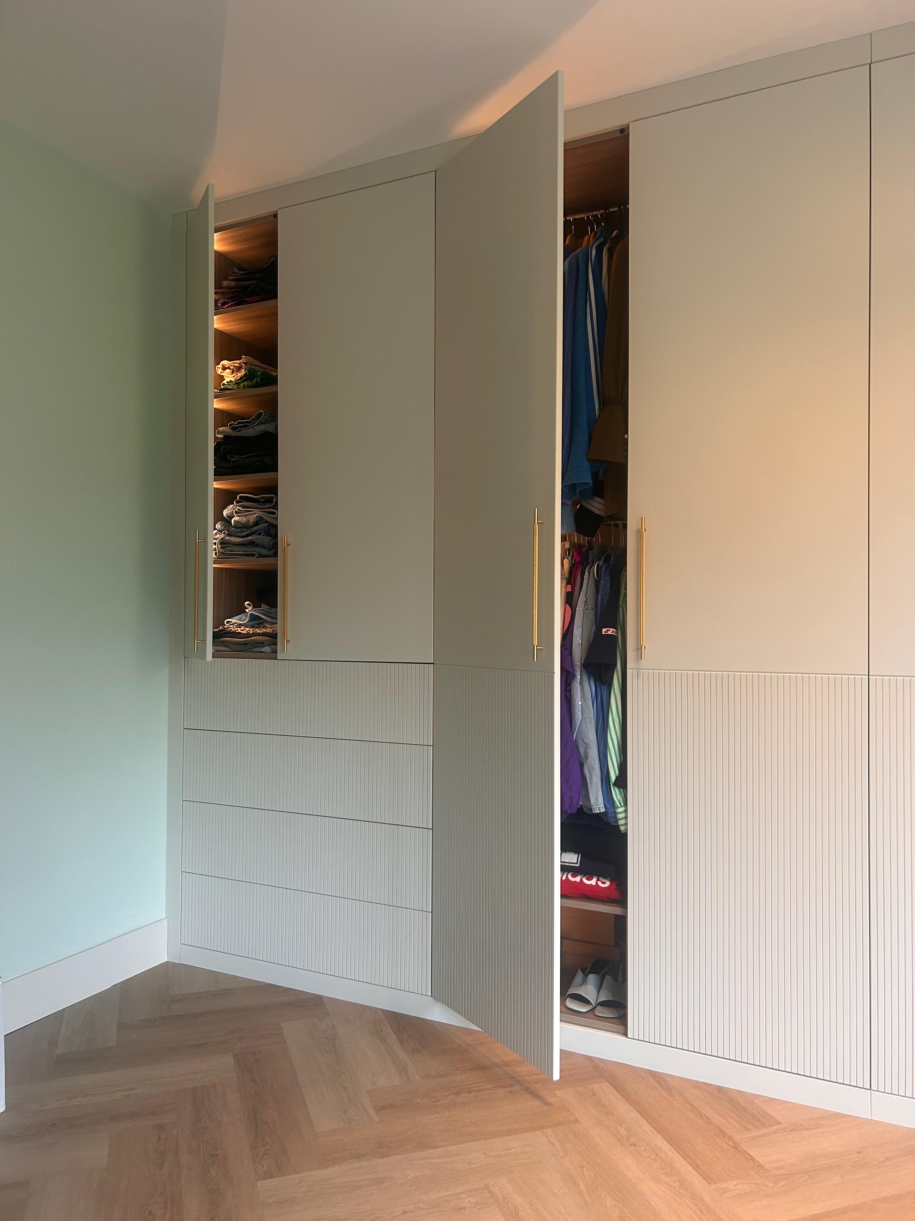 Inbouwkast met geopende deuren, interieur met planken en kledingstang